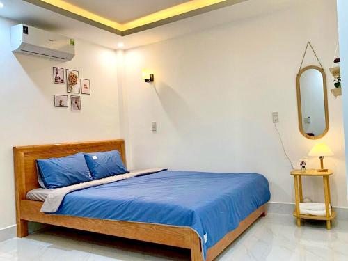 a bedroom with a bed with blue sheets and a mirror at Win House Huế in Thôn Dương Phẩm