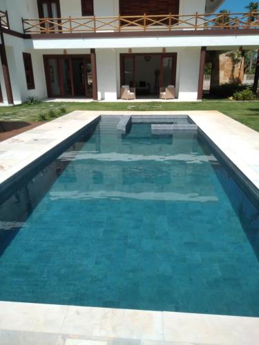 a swimming pool with blue water in front of a house at Villas de Guajirú, Casa 2 in Flecheiras