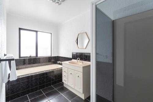 a bathroom with a tub and a sink and a mirror at Stylish Family Retreat by Hawley Beach in Hawley Beach
