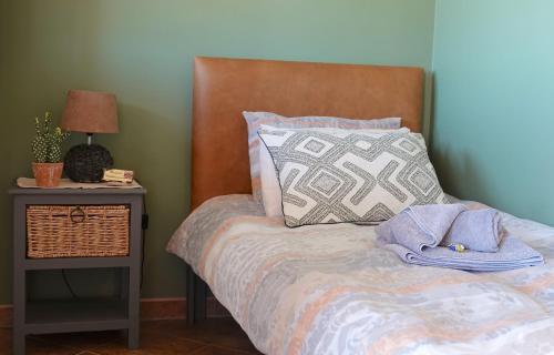 a bed with a wooden headboard next to a table with a lamp at Rooisand Desert Ranch in Chausib