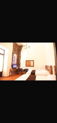 a bedroom with two beds and a stone wall at Villa villar in Querétaro