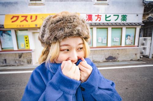 a woman wearing a fur hat and a blue coat at VacationHouse朔 海街さんぽ道 in Nahari