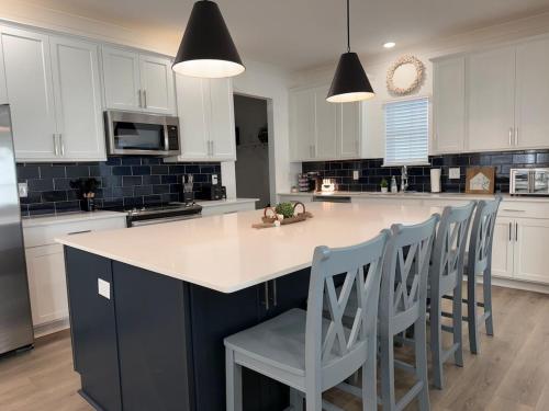 a kitchen with white cabinets and a island with chairs at Sea La Vie - Large Family Friendly 4BR 10 Bed Pool and Bay Access in Orange Beach