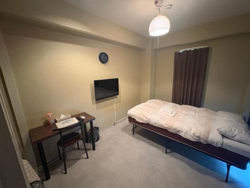 a bedroom with a bed and a desk and a tv at Hotel Yumeya in Fukuoka