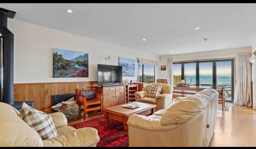 a living room with two couches and a television at Lakefront House Stunning Sunsets in Waitahanui
