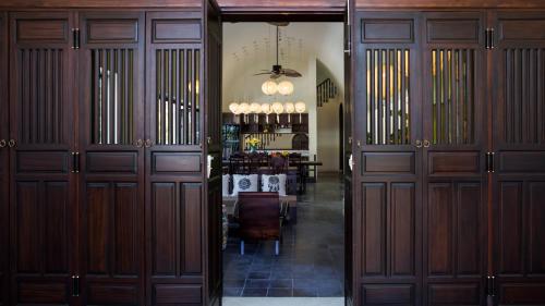a hallway with wooden doors and a dining room at Hoianoi Villa_A Little Hoi An_Entire villa in Hoi An