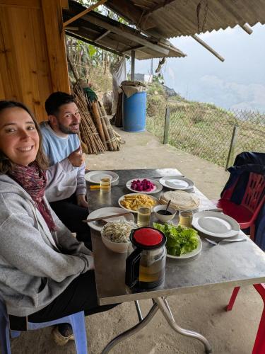 a man and a woman sitting at a table with food at Homestay & Trekking Sapa Tom Tom in Sa Pả