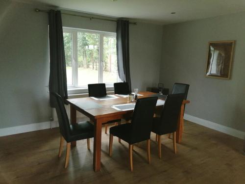 a dining room table with black chairs and a window at Ballyhoura Country Kildorrery, beautiful 5 bed in Kildorrery