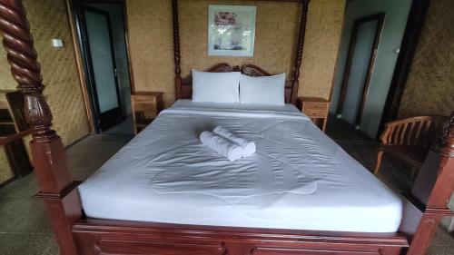 a large bed with a wooden frame and white sheets at Villa Gajah Mas in Baturiti