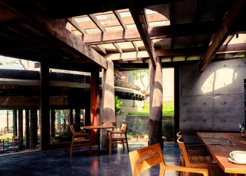 a patio with wooden tables and chairs under a roof at Vows Villa Beachfront in Ban Bang Po