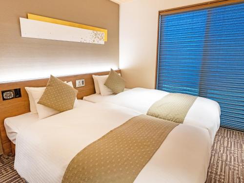 two white beds in a room with a window at Stay SAKURA Kyoto Higashi Hongan-ji I in Kyoto