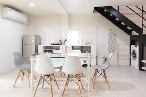 a kitchen with white chairs and a dining table at Baan Khun Pra APT No4 Duplex 3BR in Bangkok
