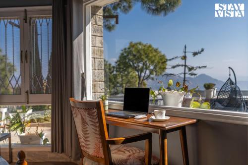 a laptop computer sitting on a table in front of a window at StayVista at Serene with Outdoor Bonfire in Barog