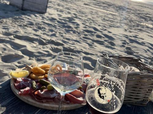 - une assiette de nourriture et de verres à vin sur la plage dans l'établissement Charmante maison moderne près de la plage à Berck - FR-1-646-81, à Berck-sur-Mer