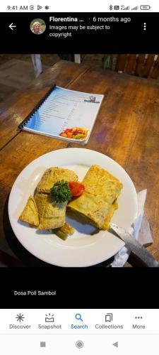 a white plate of food on a wooden table at Aaliya Bay in Arugam Bay