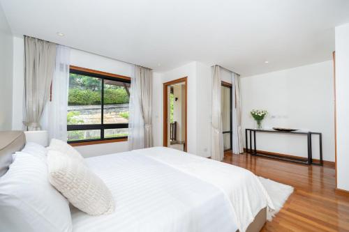 a white bedroom with a large bed and a window at Luxury 2 Bedrooms Villa Bangtao in Ban Pa Khlok