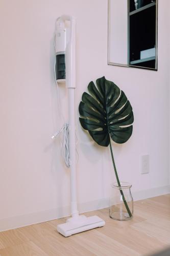 a phone and a plant in a vase on a table at Minimalist Loft Namba Compact Studio with a 24-hour Gym MA1003 in Osaka