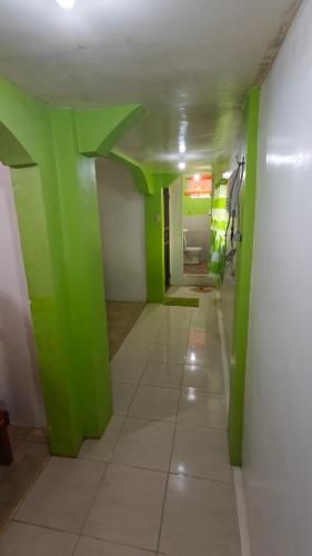 a hallway with green walls and a white tile floor at Guanna's Place Room and Resto Bar in Malapascua Island
