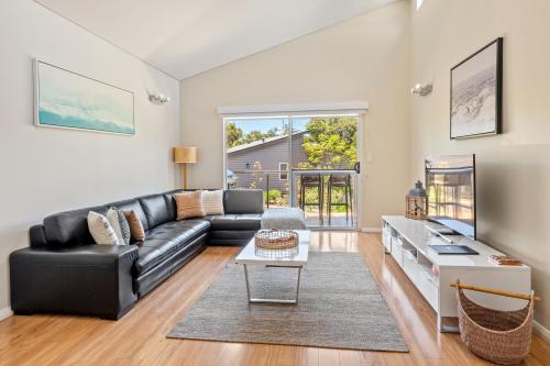 a living room with a black leather couch and a table at Villa Sedici @ Cape Villas Dunsborough in Dunsborough