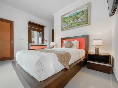 1 dormitorio con 1 cama blanca grande con almohada naranja en Kayangan Saba Villa, en Keramas