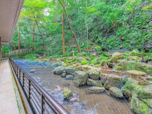 a bridge over a river with rocks and trees at Hakoneji Kaiun in Hakone