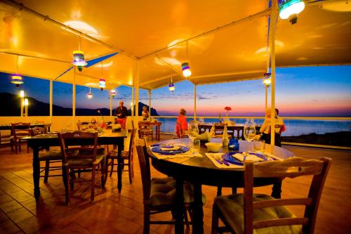 a restaurant with tables and chairs with a view of the ocean at Hotel Pocho in San Vito lo Capo