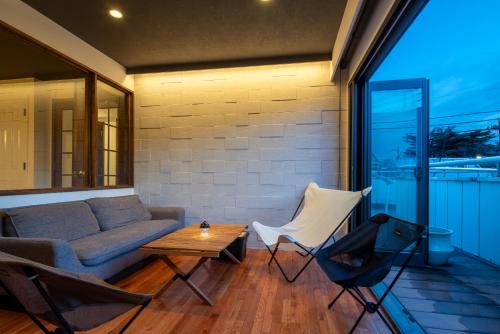 a living room with a couch and a table and chairs at PanomaStays in Chofu