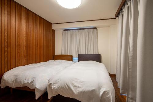a bedroom with a white bed and a window at PanomaStays in Chofu