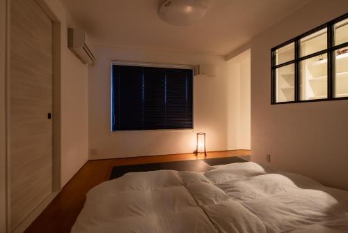 a bedroom with a white bed and a window at PanomaStays in Chofu