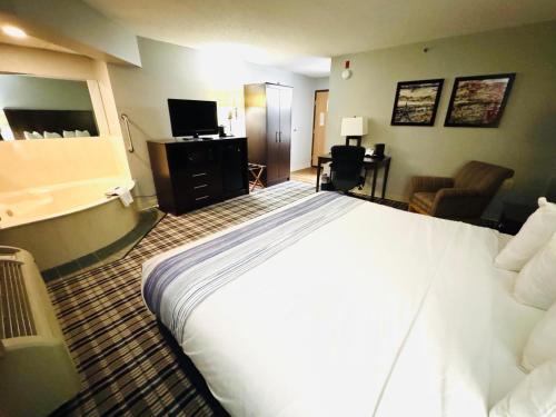 a hotel room with a large bed and a living room at AmericInn by Wyndham Ames in Ames