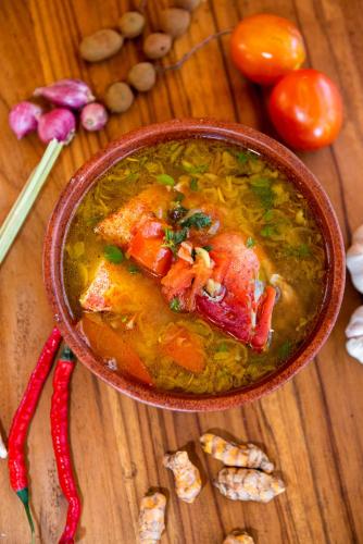a bowl of soup on a wooden table with tomatoes at Golo Nuk in Komodo Labuan Bajo Airport