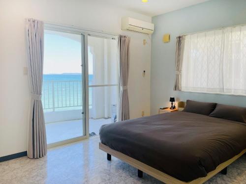 a bedroom with a large bed and a large window at Ocean Terrace金武 in Kin