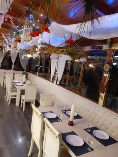 a restaurant with white tables and chairs and a large window at Hotel Bar Restaurant Stone Dream in Udënisht