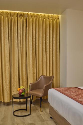 a bedroom with a bed and a chair and a table at Grand Continent Mysore A Sarovar Portico Affiliate Hotel in Mysore