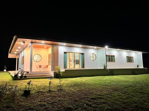 a large white house with lights on it at night at Japanese-inspired minimalistic house in Ban Bang Mak