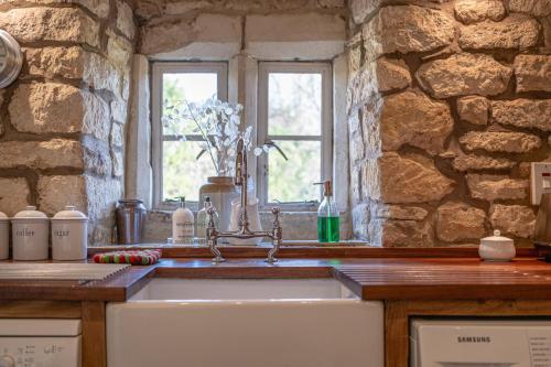 a kitchen with a sink and a stone wall at Orchard Cottage - Beautiful Home near Broadway! in Weston Subedge