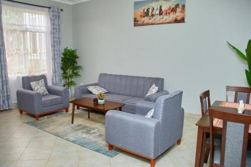 a living room with a couch and two chairs and a table at Mvule Homes in Arusha