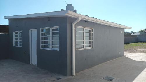 ein graues Gebäude mit zwei Fenstern und einer Tür in der Unterkunft Estrella del Faro in Mar del Plata