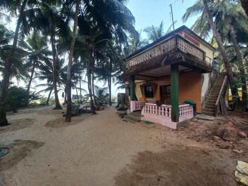 een klein huis aan het strand met palmbomen bij Malvan Beach Homestay in Malvan