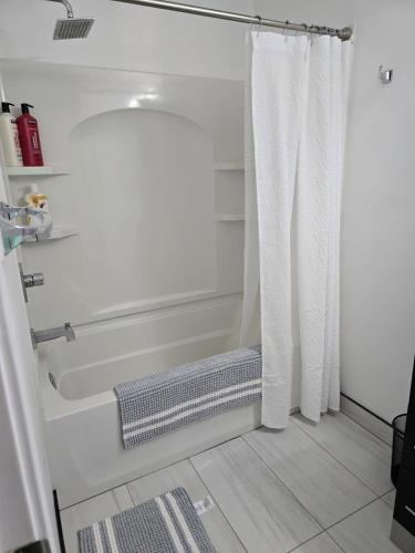a bathroom with a tub and a shower curtain at Full House - Main Floor in Regina
