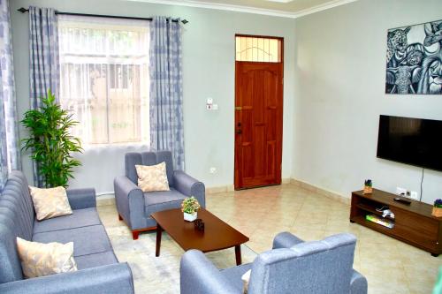 a living room with a couch and chairs and a tv at Mvule Homes in Arusha