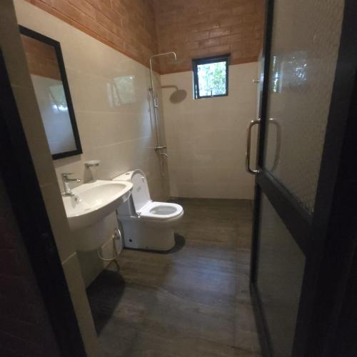 a bathroom with a white toilet and a sink at Life of Leisure Wilpattu in Pahala Maragahawewa