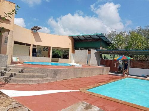 a building with a swimming pool and a person standing next to it at Kids-Dee Home in Sathani Padang Besa