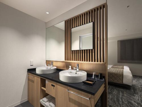 a bathroom with two sinks and a mirror at Villa Fontaine Grand Osaka Umeda in Osaka