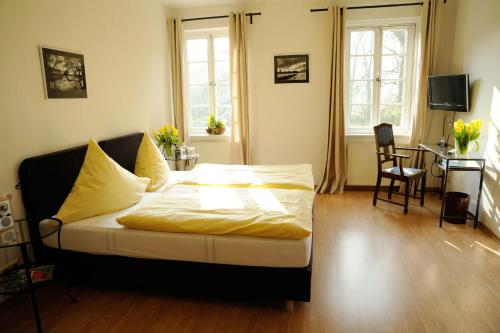 a bedroom with a bed and a desk and two windows at Klosterschänke Hude Hotel Ferienwohnungen Restaurant Café in Hude