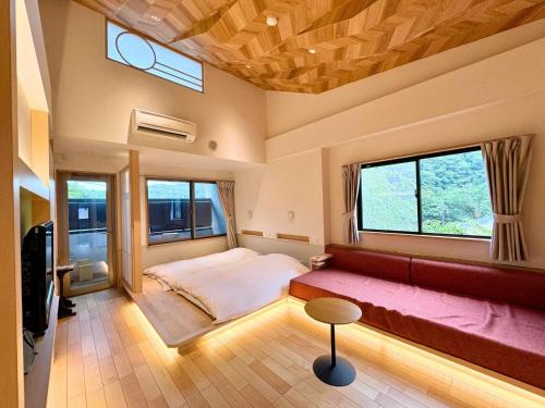 1 dormitorio con cama, sofá y ventanas en Hidamari Ichinoyu, en Hakone