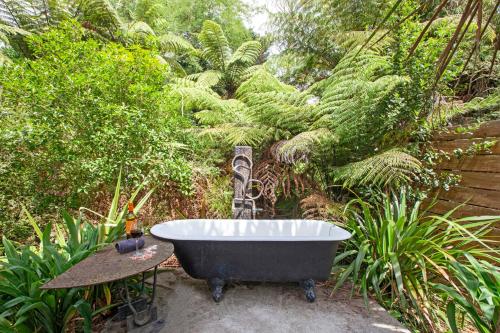 a bath tub sitting in the middle of a garden at Boutique Country Retreat -Outdoor bath in Hamilton