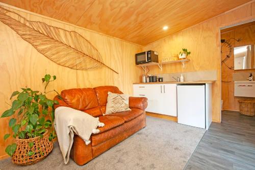 a living room with a brown leather couch and a kitchen at Boutique Country Retreat -Outdoor bath in Hamilton