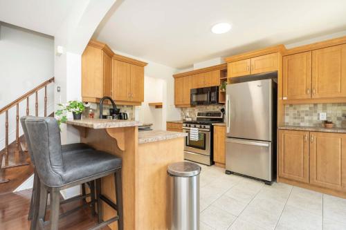 a kitchen with wooden cabinets and a stainless steel refrigerator at Cozy Modern 4BR Home with Sunny Patio in Ottawa