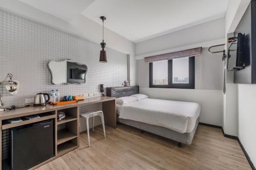 a small bedroom with a bed and a desk at CHECK inn Express Kaohsiung Love River in Kaohsiung